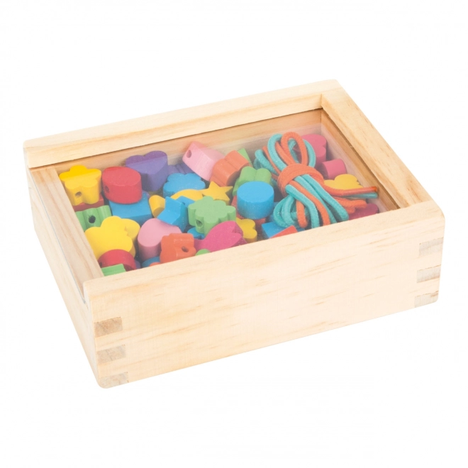 Petites perles en bois à enfiler formes dans une boîte