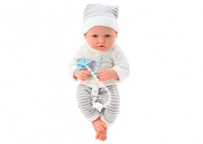 Poupée bébé réaliste en tenue blanc-gris avec bonnet et tétine