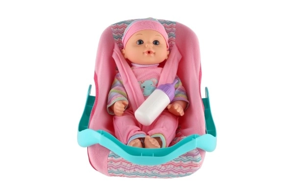 Poupée bébé 30cm en plastique dans un porte-bébé/siege auto avec biberon en blister