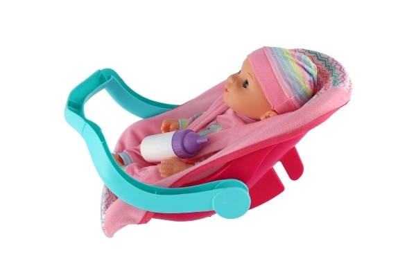 Poupée bébé 30cm en plastique dans un porte-bébé/siege auto avec biberon en blister