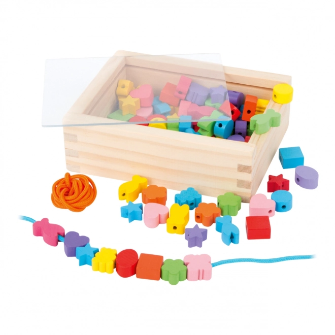 Petites perles en bois à enfiler formes dans une boîte